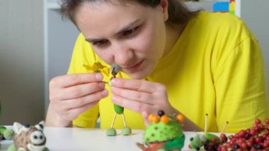 A woman creates a figure of a man from acorns and matches. Autumn crafts