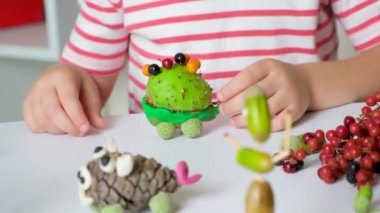 A 5-year-old boy plays with a chestnut hedgehog figure. Autumn crafts with your own hands.