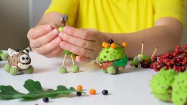 A woman creates a figure of a man from acorns and matches. Autumn crafts