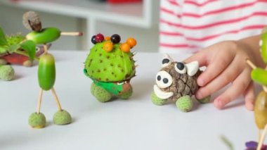 A preschool boy plays with animal figurines made of acorns, chestnuts and cones