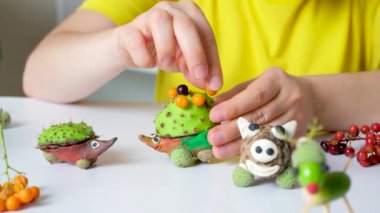 Bir kadın plasticine ve kestaneden bir kirpi yaratıyor rowan üzümlü, sonbahar işçiliğiyle.