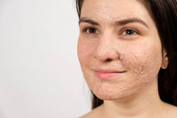 A young brunette woman makes cleansing facial treatments - a mask or scrub to cleanse and nourish the skin