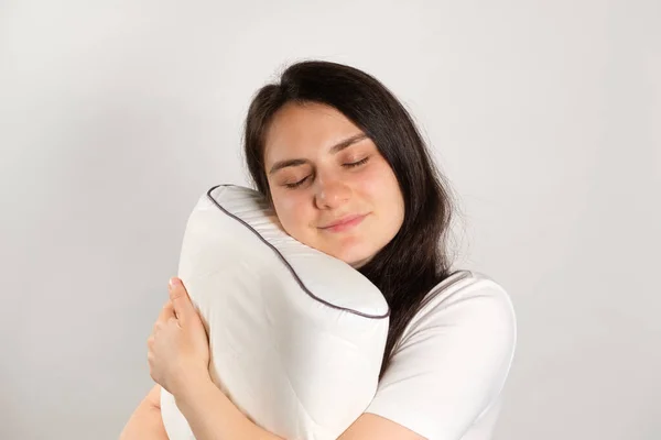 一个女人抱着一个用白色背景的记忆泡沫做成的矫形外科枕头 选择枕头以促进健康睡眠 — 图库照片