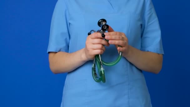 Médico Uniforme Azul Segura Estetoscópio Suas Mãos Close Fundo Azul — Vídeo de Stock