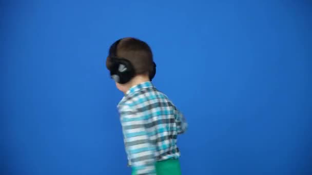 Хлопчик Навушниках Крутиться Синьому Фоні Намагаючись Падати — стокове відео
