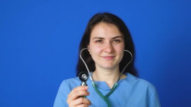 Steteskoplu bir doktor ya da hemşire mavi arka planda gülümsüyor.