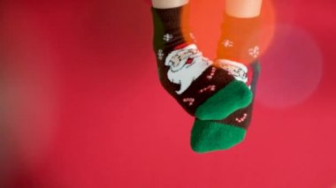 Noel çoraplı kadın ayakları, kırmızı arka planda Noel Baba, dans eden bacaklar..
