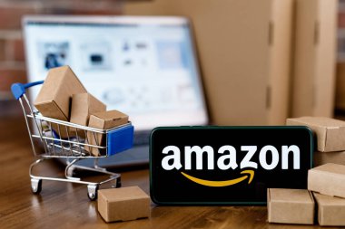 Kazan, Rusya - Ekim 02, 2021: Amazon dünyanın en büyük e-ticaret platformu pazarlarından biri olan bir Amerikan şirketidir. Ekranda Amazon logosu olan akıllı telefon, alışveriş arabası ve dizüstü bilgisayar..