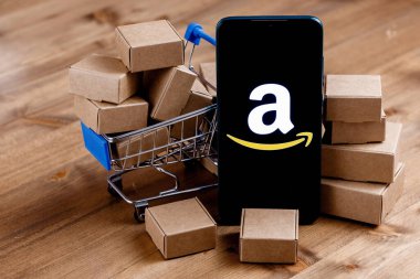 Kazan, Rusya - Ekim 02, 2021: Amazon dünyanın en büyük e-ticaret platformu pazarlarından biri olan bir Amerikan şirketidir. Ekranda Amazon logosu olan akıllı telefon, alışveriş arabası ve paketler..