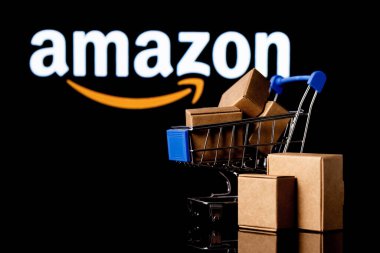 Kazan, Rusya - Ekim 02, 2021: Amazon dünyanın en büyük e-ticaret platformu pazarlarından biri olan bir Amerikan şirketidir. Amazon logolu siyah arka planda paketler olan alışveriş arabası..
