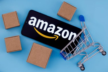 Kazan, Rusya - Ekim 02, 2021: Amazon dünyanın en büyük e-ticaret platformu pazarlarından biri olan bir Amerikan şirketidir. Ekranda Amazon logosu olan akıllı telefon, alışveriş arabası ve paketler..