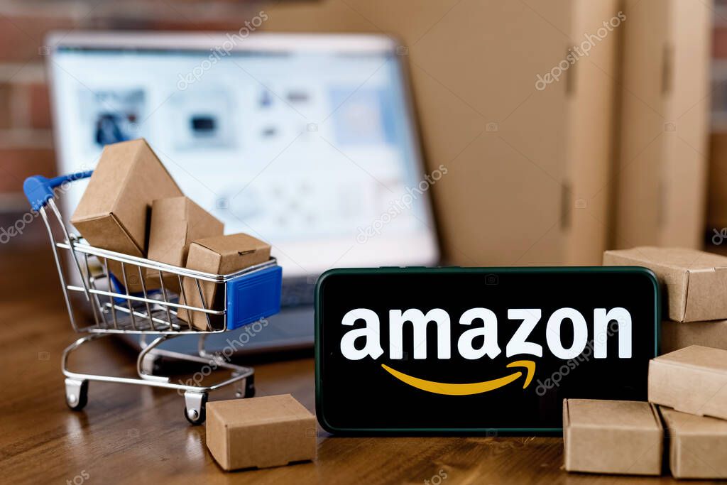 Kazan, Russia - Oct 02, 2021: Amazon is an American company, one of the world's largest e-commerce platform markets. Smartphone with Amazon logo on the screen, shopping cart and laptop.