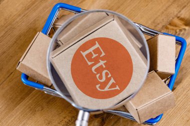 Kazan, Rusya - 6 Ekim 2021: Etsy, ABD 'li bir e-ticaret şirketidir. Alışveriş arabasındaki büyüteç altındaki kutunun üzerindeki Etsy logosunun değiştirilmiş fotoğrafı..