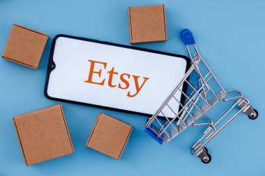 Kazan, Rusya - 6 Ekim 2021: Etsy, ABD 'li bir e-ticaret şirketidir. Ekranda Etsy logosu olan akıllı telefon, alışveriş arabası ve paketler..