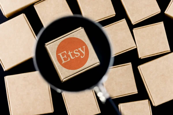 Kazan, Rusya - 6 Ekim 2021: Etsy, ABD 'li bir e-ticaret şirketidir. Paketlerle çevrili bir büyüteç altındaki kutunun üzerindeki Etsy logosunun değiştirilmiş fotoğrafı..