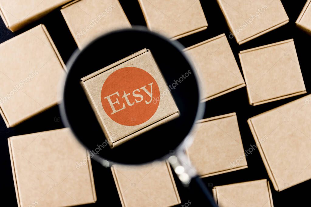 Kazan, Russia - Oct 6, 2021: Etsy is American e-commerce company focused on handmade items and craft supplies. Modified photo of Etsy logo on a box under a magnifying glass surrounded by parcels.