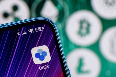 Kazan, Rusya - 7 Ekim 2021: OKEx bir kripto döviz kurudur. Akıllı telefon ekranındaki OKEx uygulaması ana kripto para birimlerinin arka planına karşı.