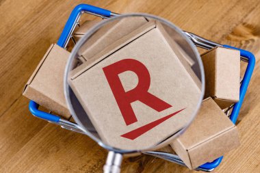 Kazan, Rusya - 12 Ekim 2021: Rakuten Grubu Japon elektronik ticaret ve çevrimiçi perakende satış şirketidir. Alışveriş arabasındaki büyüteç altındaki kutunun üzerindeki Rakuten logosunun değiştirilmiş fotoğrafı..
