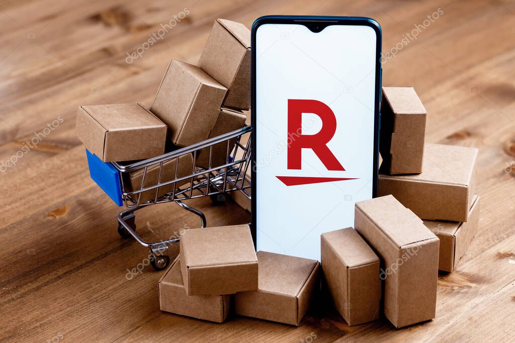 Kazan, Russia - Oct 12, 2021: Rakuten Group is Japanese electronic commerce and online retailing company. Smartphone with Rakuten logo on the screen, shopping cart and parcels.