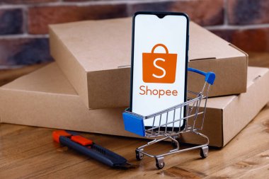 Kazan, Rusya - 14 Ekim 2021 Shopee bir e-ticaret teknoloji şirketidir. Ekranda Shopee logosu olan akıllı telefon, alışveriş arabası ve paketler..
