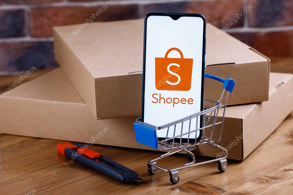 Kazan, Russia - Oct 14, 2021: Shopee is e-commerce technology company. Smartphone with Shopee logo on the screen, shopping cart and parcels.