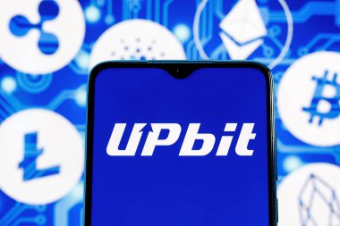 Kazan, Rusya - 15 Ekim 2021: Upbit Güney Kore kripto para birimi değişimi. Ana kripto para birimlerinin arka planına karşılık akıllı telefon ekranındaki yükseltme logosu.