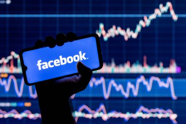 Kazan, Rusya - 19 Ekim 2021: Facebook sosyal ağ logosu olan bir akıllı telefon. Arka planda Facebook borsa çizelgesi.