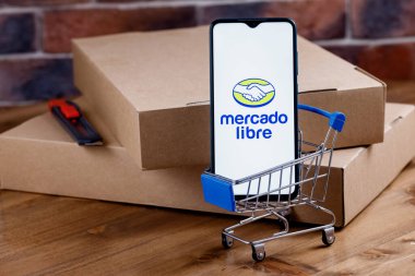 Kazan, Rusya - 22 Ekim 2021: Mercado Libre, Arjantinli çevrimiçi pazarlama şirketi. Ekranda Mercado Libre logosu olan akıllı telefon, alışveriş arabası ve paketler..