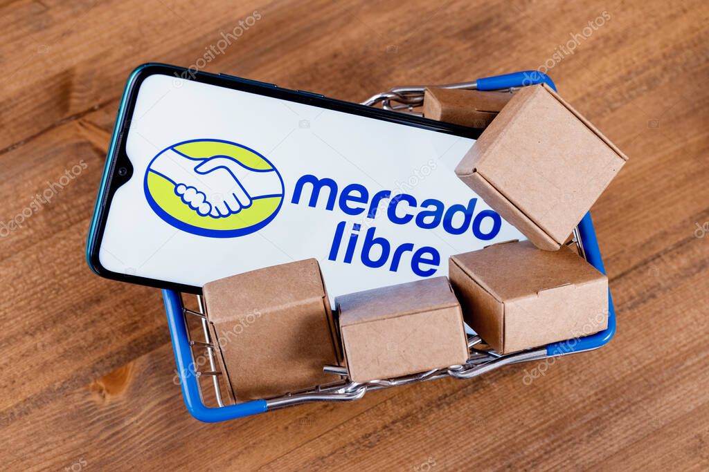 Kazan, Russia - Oct 22, 2021: Mercado Libre is Argentine company that operates online marketplaces. Smartphone with Mercado Libre logo on the screen, shopping cart and parcels.