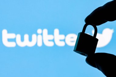 Kazan, Rusya - 23 Ekim 2021: Twitter sosyal ağ logosunun arka planında parmaklar kapalı bir güvenlik kilidi tutuyor. Twitter 'da veri güvenliği kavramı.