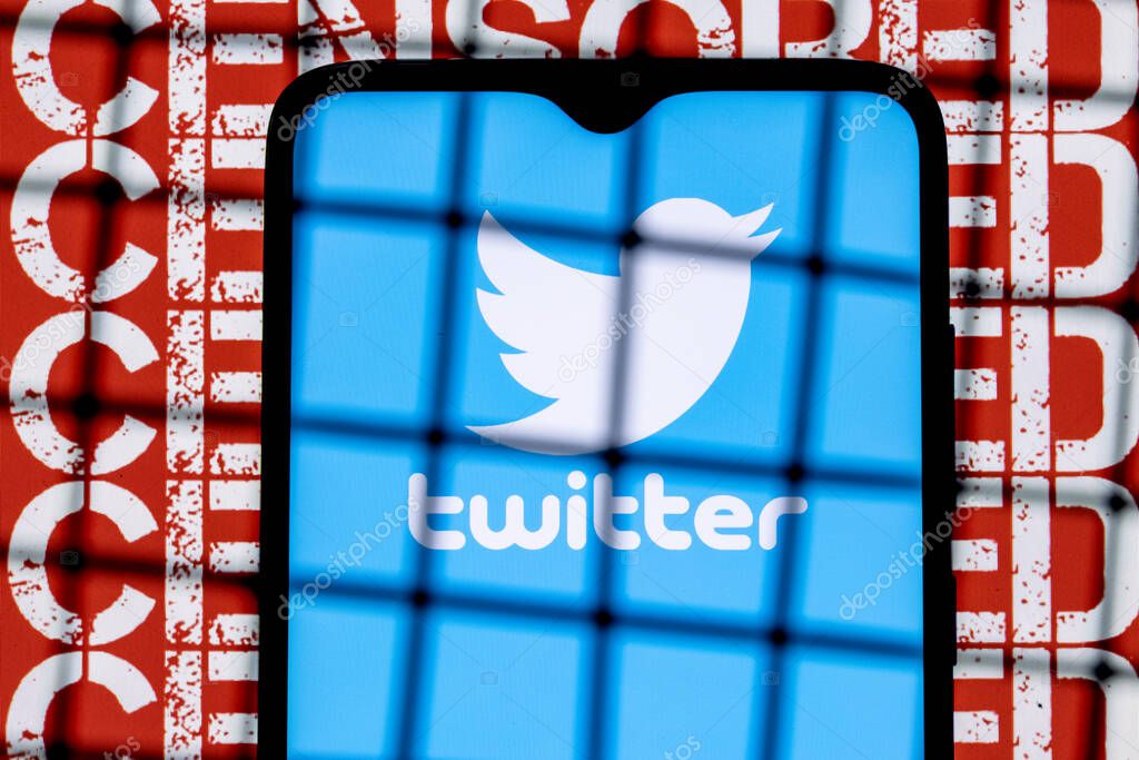 Kazan, Russia - Oct 23, 2021: Twitter social network logo on the smartphone screen behind the bars on the background with the inscription censored. The concept of Twitter censorship and prohibition.