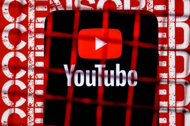 Kazan, Rusya - 24 Ekim 2021: Youtube logosu arka plandaki parmaklıkların arkasındaki akıllı telefon ekranında sansürlenmiş. Youtube sansür ve yasaklama kavramı.