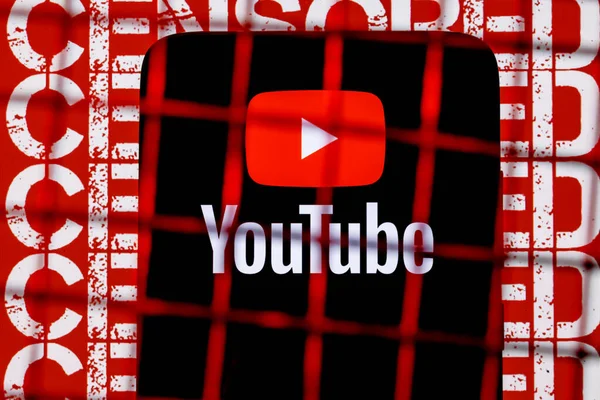 Kazan, Rusya - 24 Ekim 2021: Youtube logosu arka plandaki parmaklıkların arkasındaki akıllı telefon ekranında sansürlenmiş. Youtube sansür ve yasaklama kavramı.