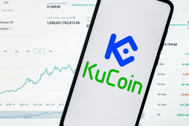 Kazan, Rusya - 26 Ekim 2021: KuCoin şifreli para değişimi. Arkaplanda KuCoin logosu olan akıllı bir telefon. KuCoin gösterge paneli.