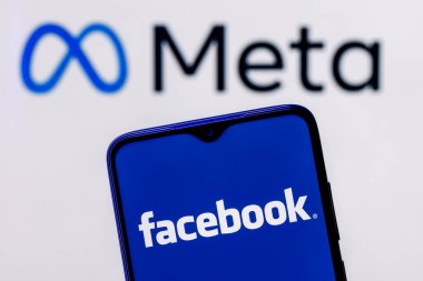 Kazan, Rusya - 28 Ekim 2021: Facebook adını Meta olarak değiştirdi. Meta logosunun arka planında Facebook logosu olan akıllı telefon.
