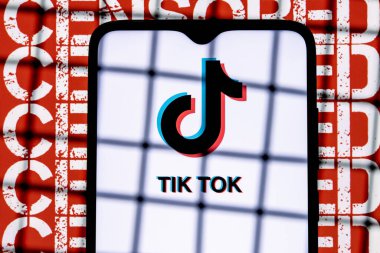 Kazan, Rusya - 31 Ekim 2021: Arkaplanda parmaklıkların arkasındaki akıllı telefon ekranındaki TikTok sosyal ağ logosu sansürlenmiş. TikTok sansür ve yasaklama kavramı.
