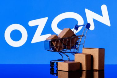 Kazan, Rusya - 10 Kasım 2021: Ozon Rus e-ticaret şirketidir. Ozon logosunun arka planında paketler olan alışveriş arabası..