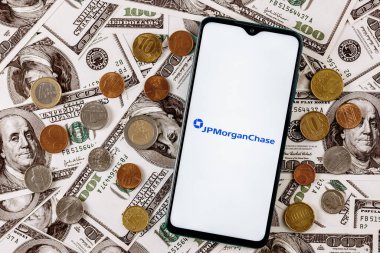 Kazan, Rusya - 24 Kasım 2021: JPMorgan Chase bankasının logosuna sahip akıllı telefon dolar banknotlarının arka planında çeşitli metal paralarla çevrili
