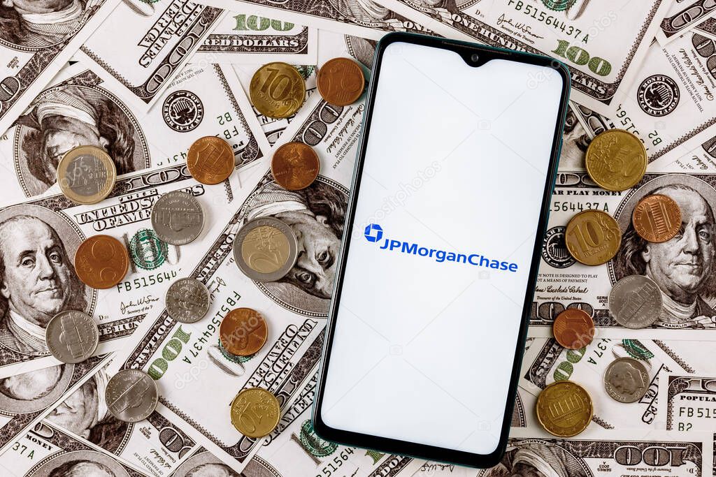 Kazan, Russia - Nov 24, 2021: Smartphone with JPMorgan Chase bank logo surrounded by variety of metal coins on background of dollar bills