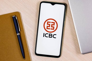 Kazan, Rusya - 29 Kasım 2021: Çin Sanayi ve Ticaret Bankası logosu olan akıllı telefon ahşap masa üzerinde dizüstü bilgisayar ve iş planlayıcısının yanında