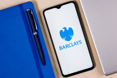 Kazan, Rusya - 03 Aralık 2021: Üzerinde Barclays banka logosu olan akıllı telefon ahşap masa üzerinde dizüstü bilgisayar ve iş planlayıcısının yanında