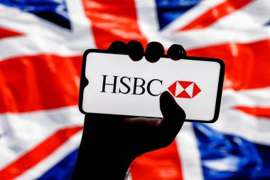 Kazan, Rusya - 16 Ocak 2022: İngiliz bayrağının arka planında sıkıca bağlı HSBC banka logosu bulunan akıllı telefon