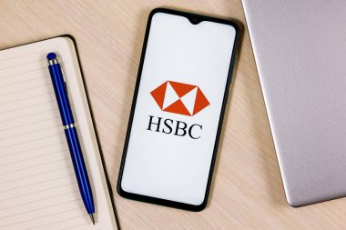 Kazan, Rusya - 16 Ocak 2022: Üzerinde HSBC banka logosu olan akıllı telefon ahşap masa üzerinde dizüstü bilgisayar ve iş planlayıcısının yanında