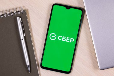 Kazan, Rusya - 27 Ocak 2021: Üzerinde Sberbank logosu olan akıllı telefon dizüstü bilgisayar ve iş planlayıcısının yanında.