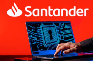 Kazan, Russia - Feb 27, 2022: Laptop with lock symbol on screen on background of  Santander bank logo. Finger points to lock symbol. Concept of data hacking. clipart