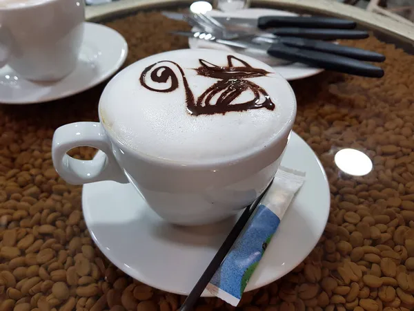 Filiżanka kawy cappuccino na talerzu na stole z ziarnem kawy — Zdjęcie stockowe