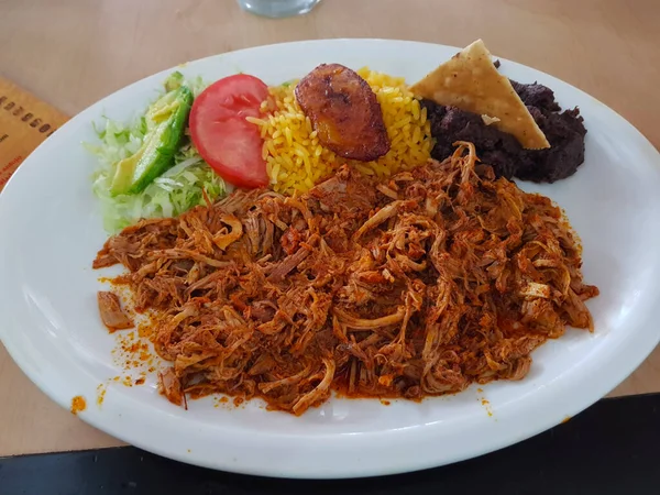 Cochinita Pibil adında bir yemek, yanında salata, pirinç ve fasulye ile domuz eti.