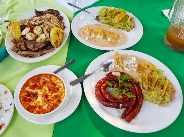 A la parrilla varios platos con carne, queso derretido, guacamole, chorizo y frijoles — Foto de Stock