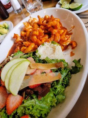 İçinde salata ve ekmek olan baharatlı karides tabağının dikey görüntüsü.