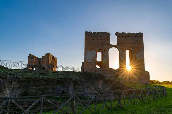 Villa dei Quintili, Roma, termal banyolar, günbatımında güneş batımında harabelerden ve Via Appia 'daki mavi gökyüzünden yükselirken kaldaryumun tuğla binasının gösterişli bir panoramik görüntüsü..